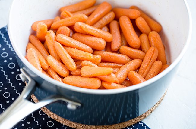 Overhead picture of candied carrots being cooked in a blue saucepan