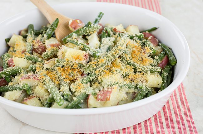 White casserole dish filled with fresh green bean casserole and red potatoes