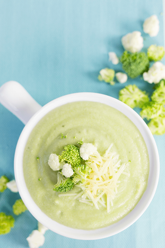 Overhead picture of white bowl of vegetable soup on blue tablecloth