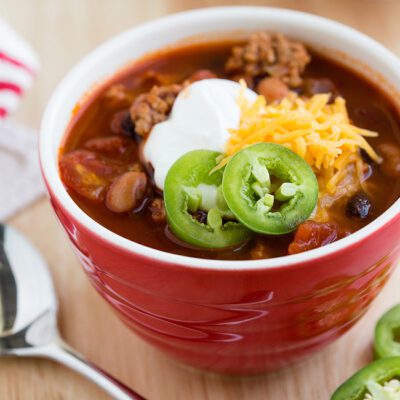 Red bowl filled with turkey chili on a wooden table