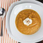 Square overhead image of butternut squash soup in large white bowl