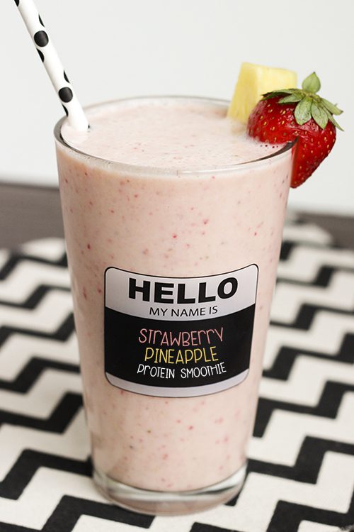 Tall glass of strawberry pineapple smoothie on a black and white chevron cloth