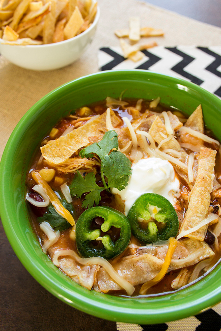 Up close picture of a green bowl filled with slow cooker chicken tortilla soup