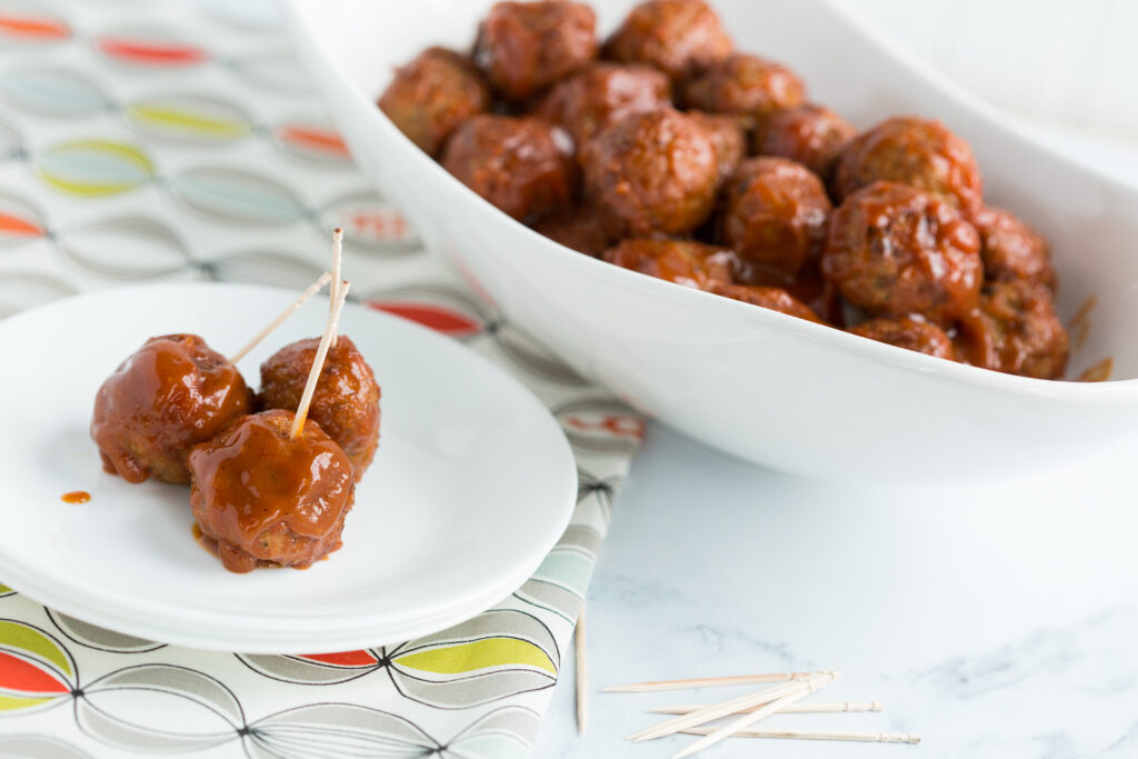 Up close picture of buorbon meatballs in white bowls on a white table