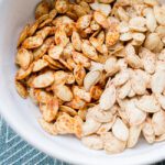 Up close picture of roasted pumpkin seeds in a white bowl