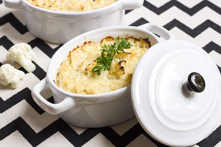 White crock sitting on black and white cloth filled with mashed cauliflower