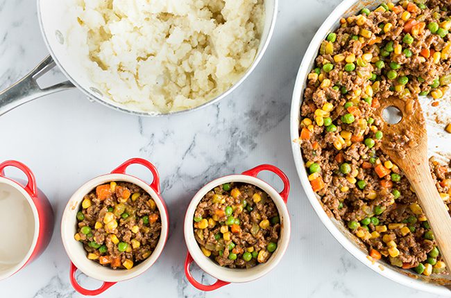 Filling mini crocks with ingredients for shepherds pie recipe