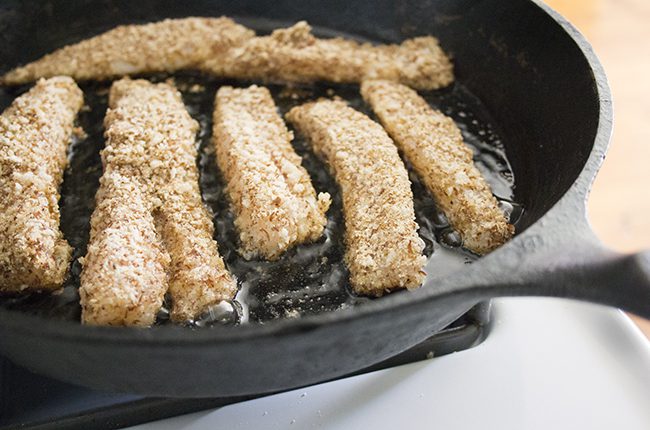 Fish sticks being cooked in a cast iron skillet