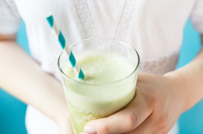 Woman holding glass of green smoothie