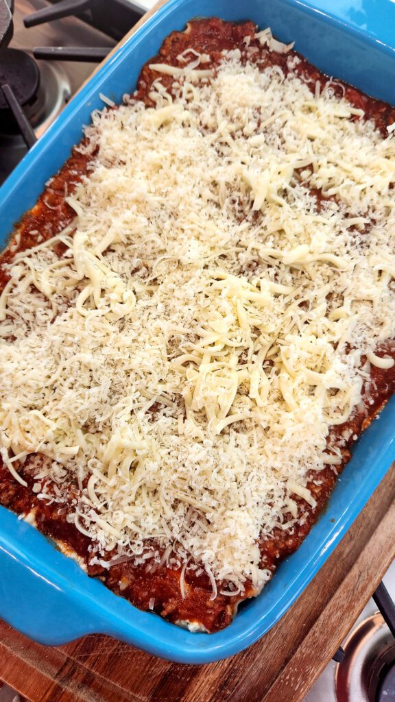 Lasagna topped with cheese, ready for the oven